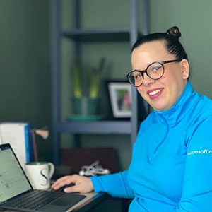 A woman sitting by a computer and smiling