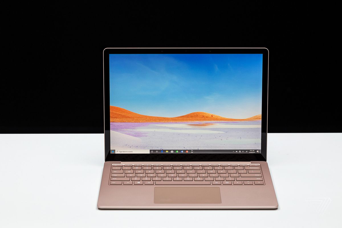 A gold Microsoft Surface Laptop 3 on a white table in front of a black background