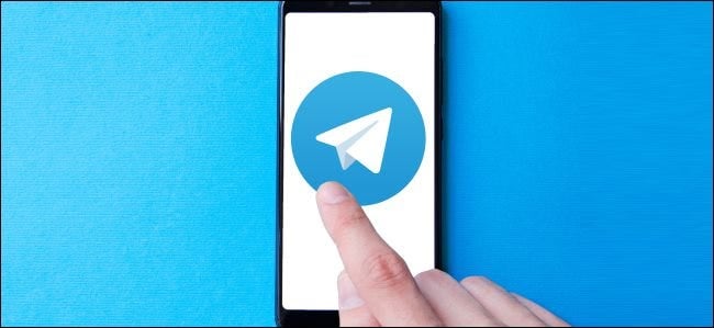 A finger tapping a large Telegram app icon on a smartphone.