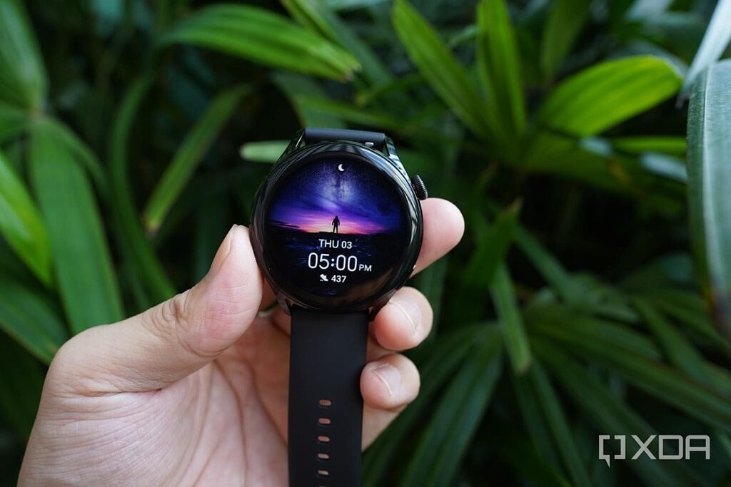 The Huawei Watch 3 with an active watch face in front of a large plant. 