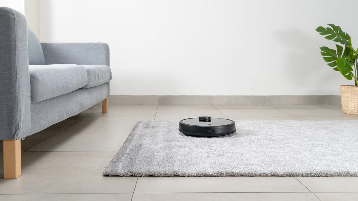 A Wyze robot vacuum running through a living room.
