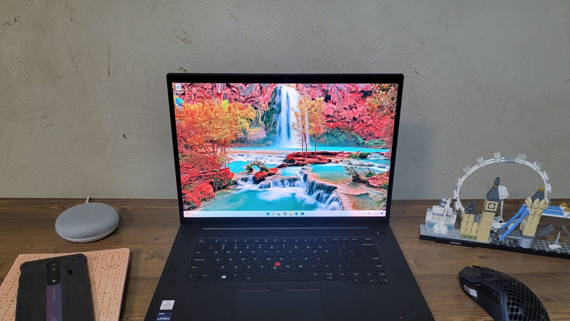 Lenovo ThinkPad X1 Extreme Gen 5 sitting on wooden desk with waterfall wallpaper shown on display