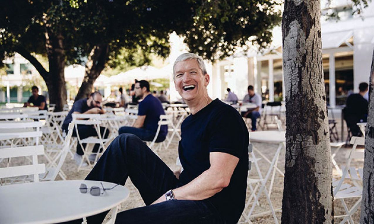 Tim Cook sitting at a table outside the Apple Park headquarters 