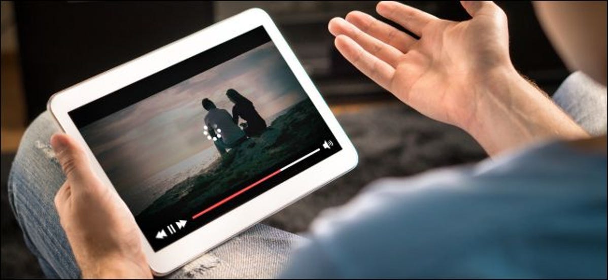 Man's hands holding a tablet showing buffering video.