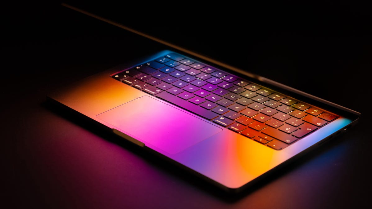 An Apple MacBook with the laptop partially lifted and the display's light reflected on the keyboard.