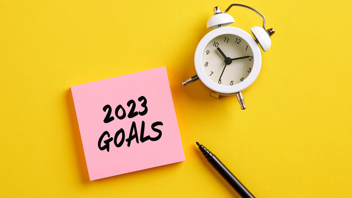 A clock,, next to a post-it note with "2023 goals"