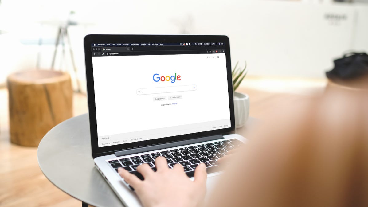 Woman typing on a laptop with Google search open in browser.