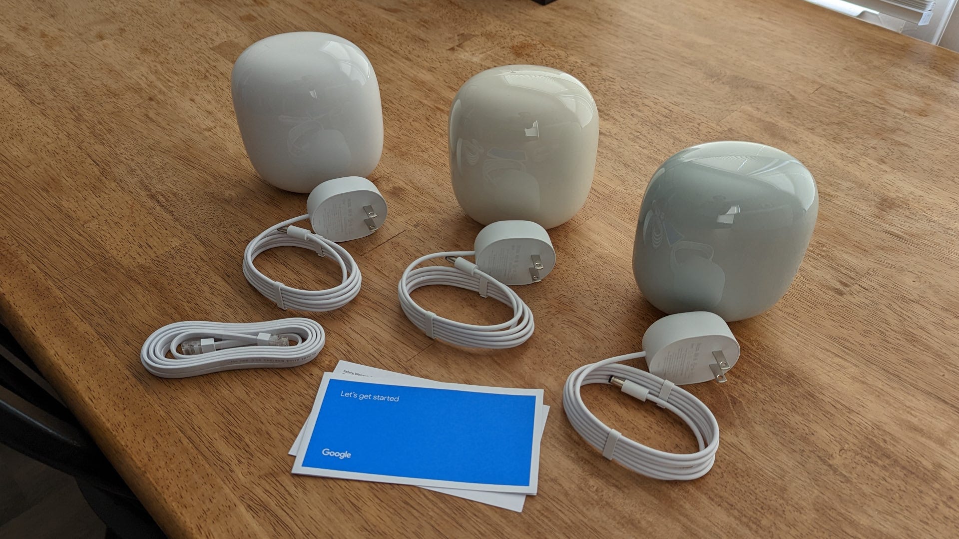 Contents of a Nest Wifi Pro three-pack, including routers, power cords, Ethernet cable, and manuals.