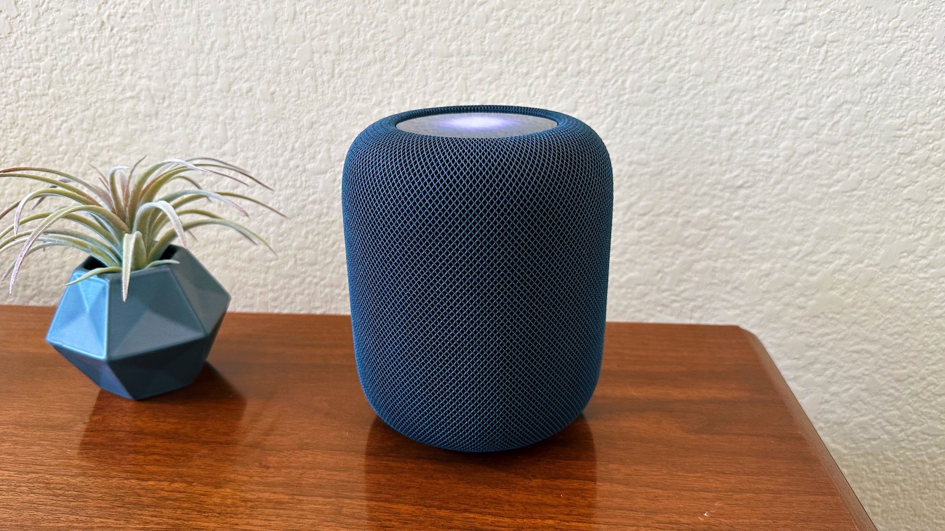 A HomePod showing Siri activated on the top screen.
