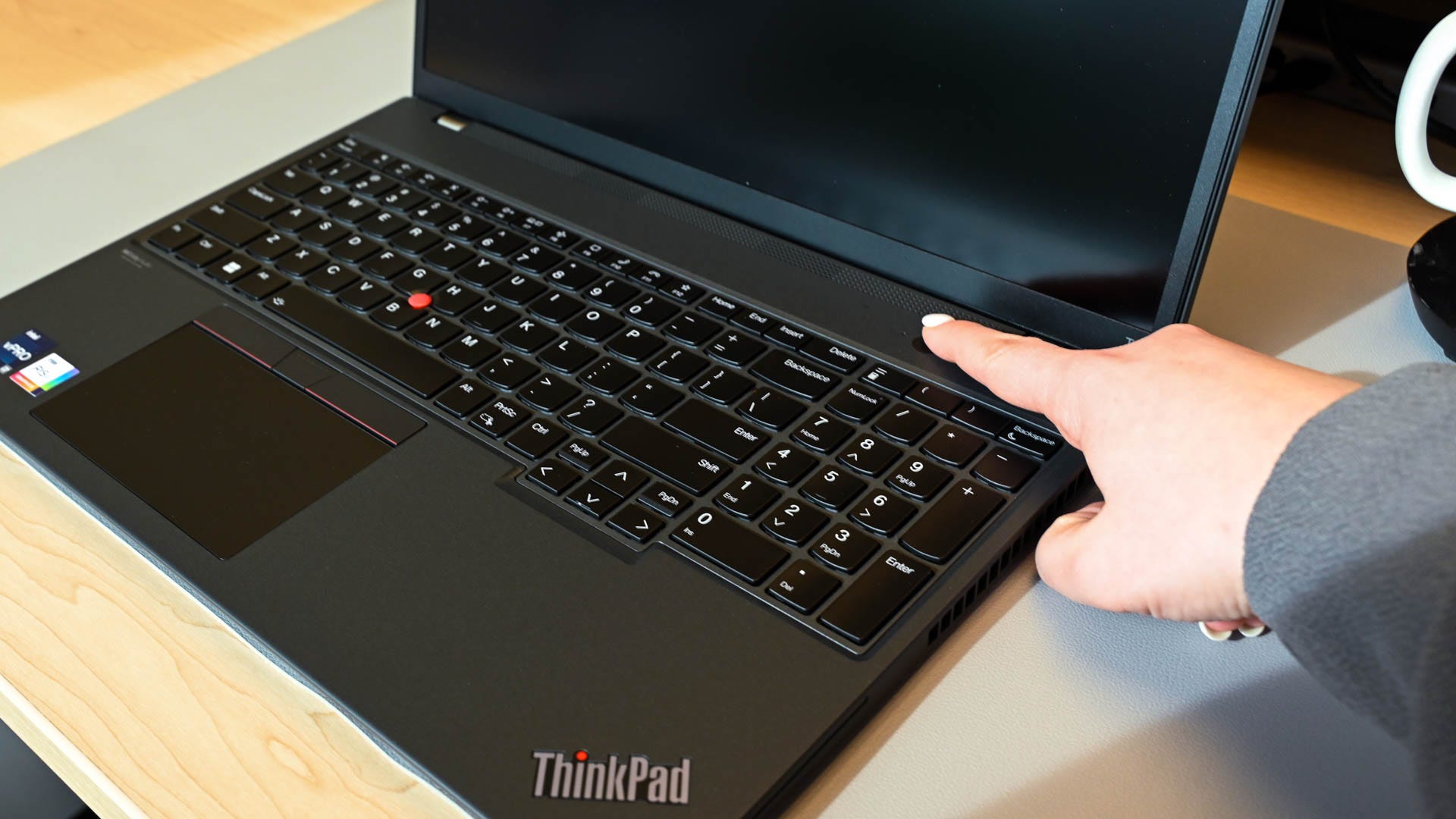 Person pressing the power button to turn on the Lenovo ThinkPad T16 Gen 1.
