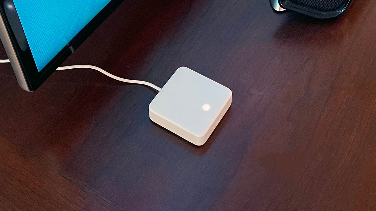 SwitchBot Hub Mini on a table next to a TV and soundbar