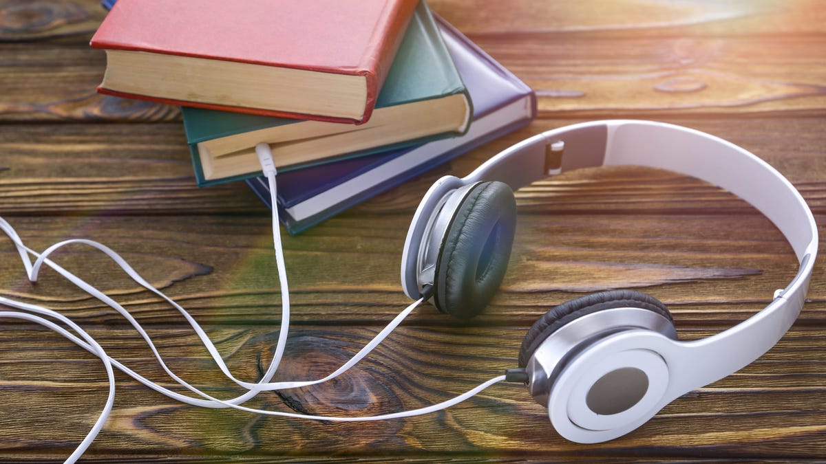 A pair of headphones connected to physical books.