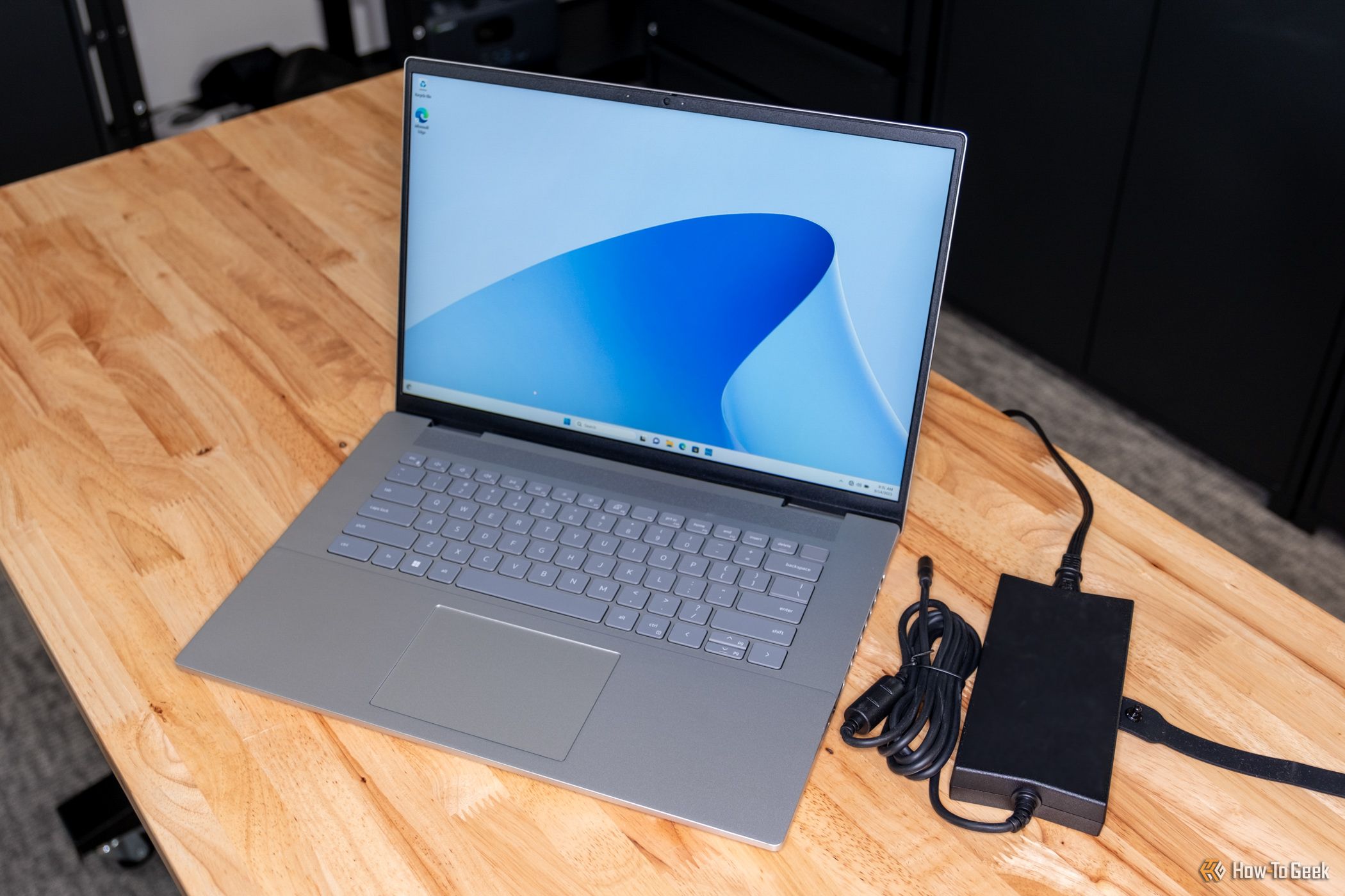 A Dell Inspiron 16 Plus 7630 on a table with its power pack to the side.