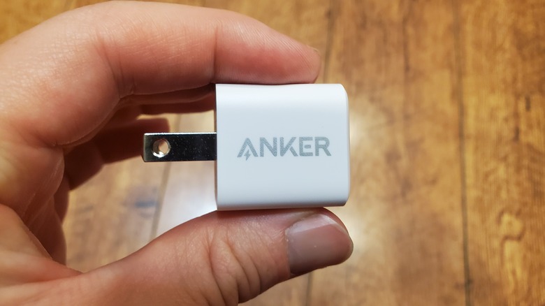 hand holding small white Anker charger