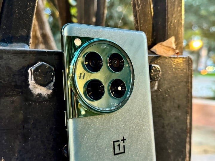 OnePlus 12 Flowy Emerald leaning against post showing closeup of camera module.