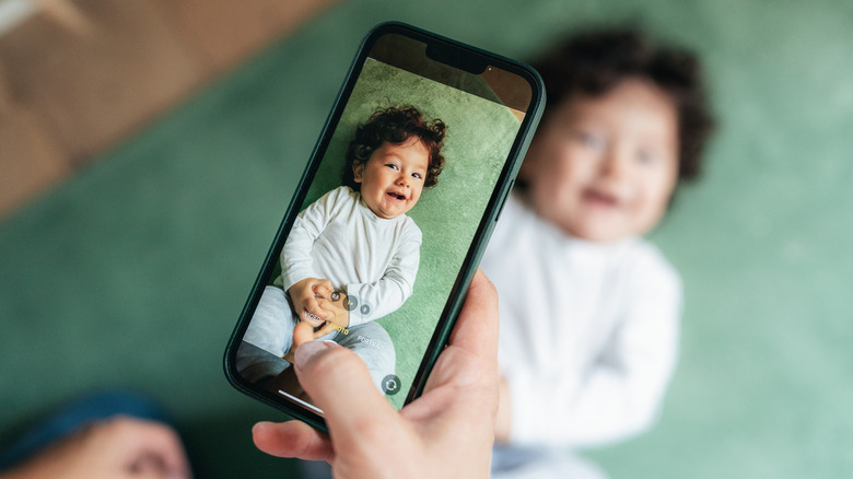 Person taking a smartphone photo of a baby