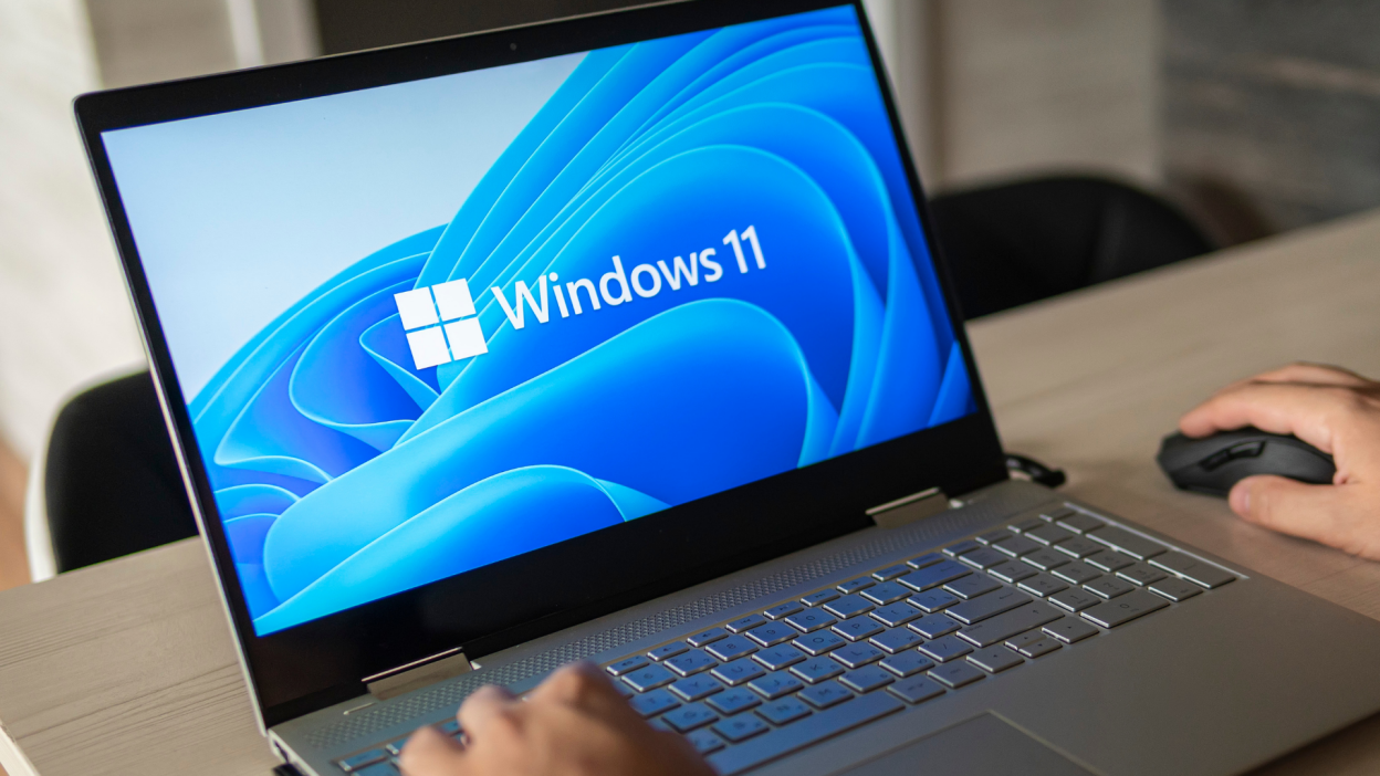 A photograph of a laptop displaying the Windows 11 logo