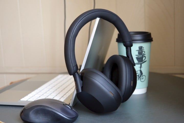 Sony WH-1000XM5 wireless headphones next to a laptop, mouse, and coffee cup.