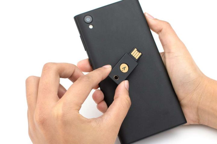 A person holding a security key over a smartphone.